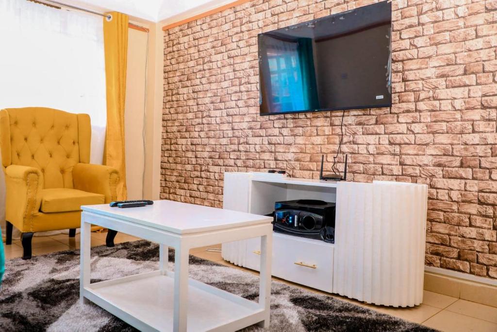 a living room with a tv on a brick wall at A&T Luxury Homestays in Kisii