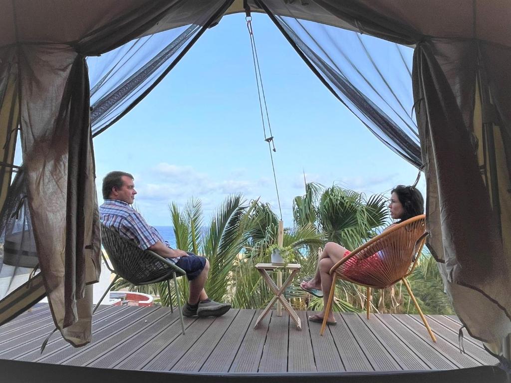 a man and a woman sitting in chairs on a deck at Porto Santo Destination in Porto Santo