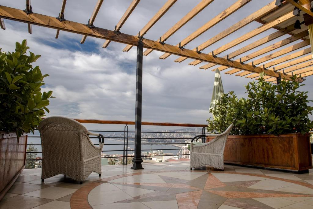an outdoor seating area with chairs, tables and umbrellas at Hotel Boutique Acontraluz in Valparaíso
