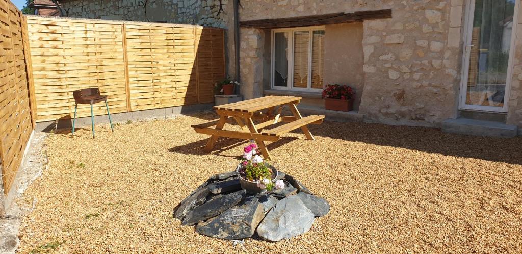 una mesa de picnic de madera en un patio con una maceta en Maison dans hameaux au calme, en Parçay-les-Pins
