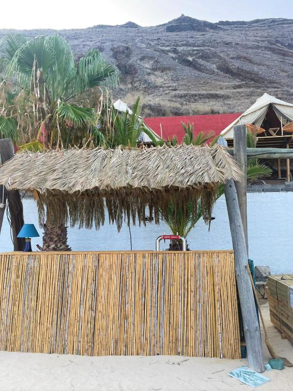 a straw hut on the beach next to the water at Porto Santo Destination in Porto Santo