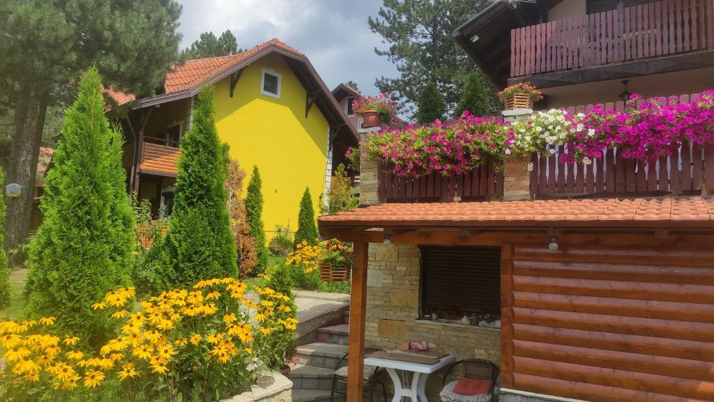 una casa amarilla con flores en un balcón en Apartment Niva, en Zlatibor