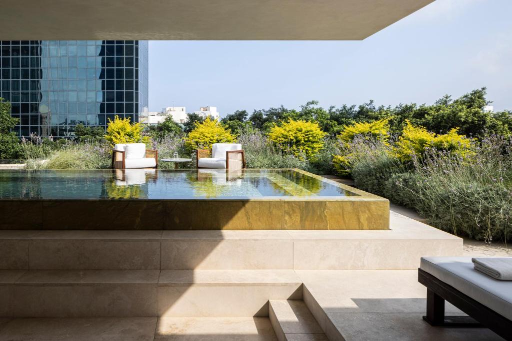 uitzicht op een zwembad met stoelen en een gebouw bij R48 Hotel and Garden in Tel Aviv