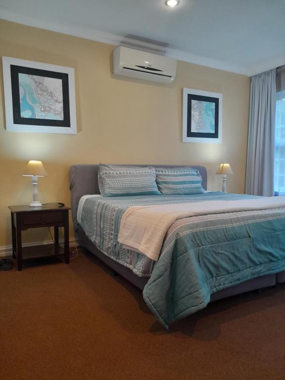 a bedroom with a bed and a table with two lamps at Sugarbush Accommodation in Vereeniging