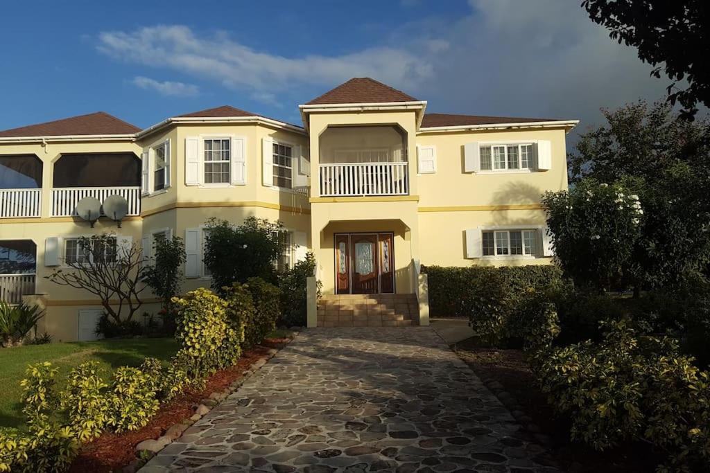 a large yellow house with a stone driveway at J's Oasis in Nevis