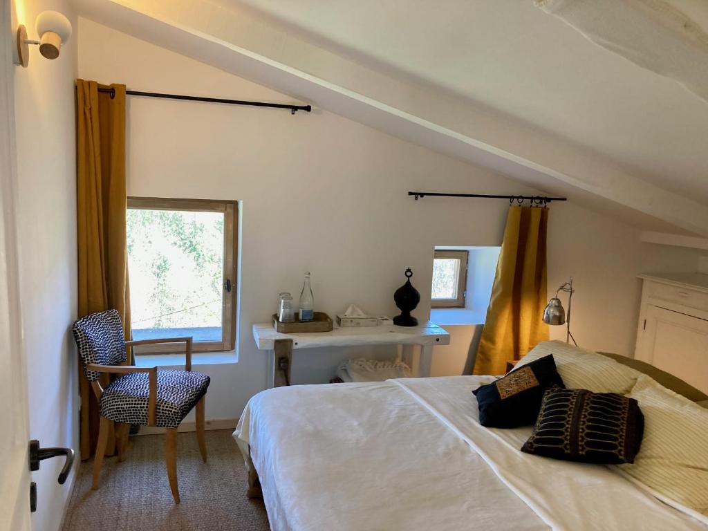 um quarto com uma cama, uma cadeira e uma janela em Molinot chambres d'hôtes em Alboussière