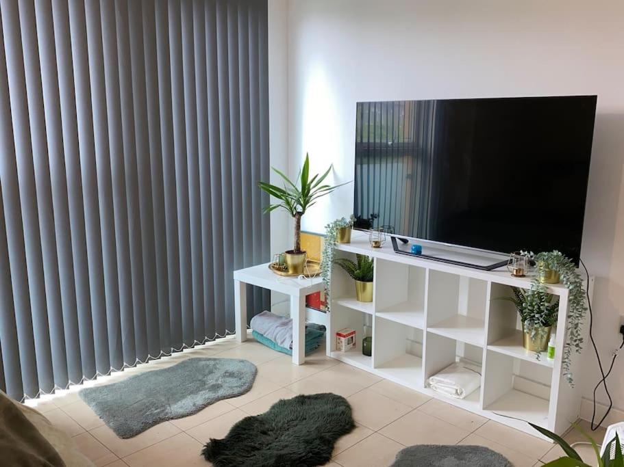 a living room with a flat screen tv and a table with rugs at Comfort Luxe in Hatch End