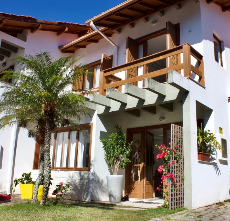 dom z palmą przed nim w obiekcie La Menina Mole Beachfront House! 4BR/4,5Baths w mieście Florianópolis