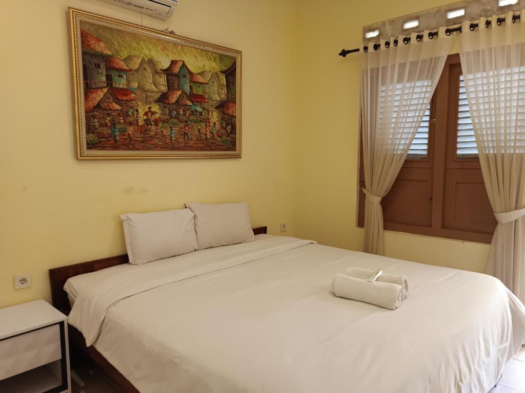 a bedroom with a white bed and a picture on the wall at Hotel Maerakatja Yogyakarta in Jetis