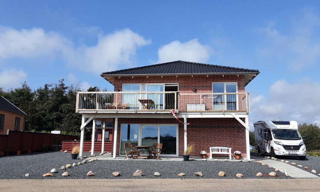 een stenen huis met een terras en een balkon bij Villa-Amby in Ringkøbing