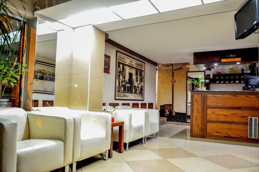 un comedor con sillas blancas y un bar en Hotel Bell, en Leskovac