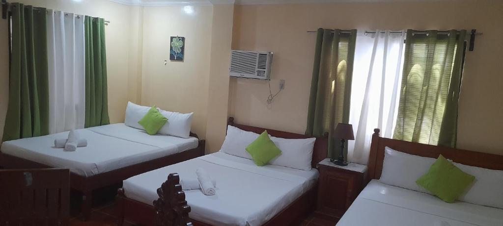 two beds with green pillows in a room at CORALYN'S PLACE family of 6 in Boracay