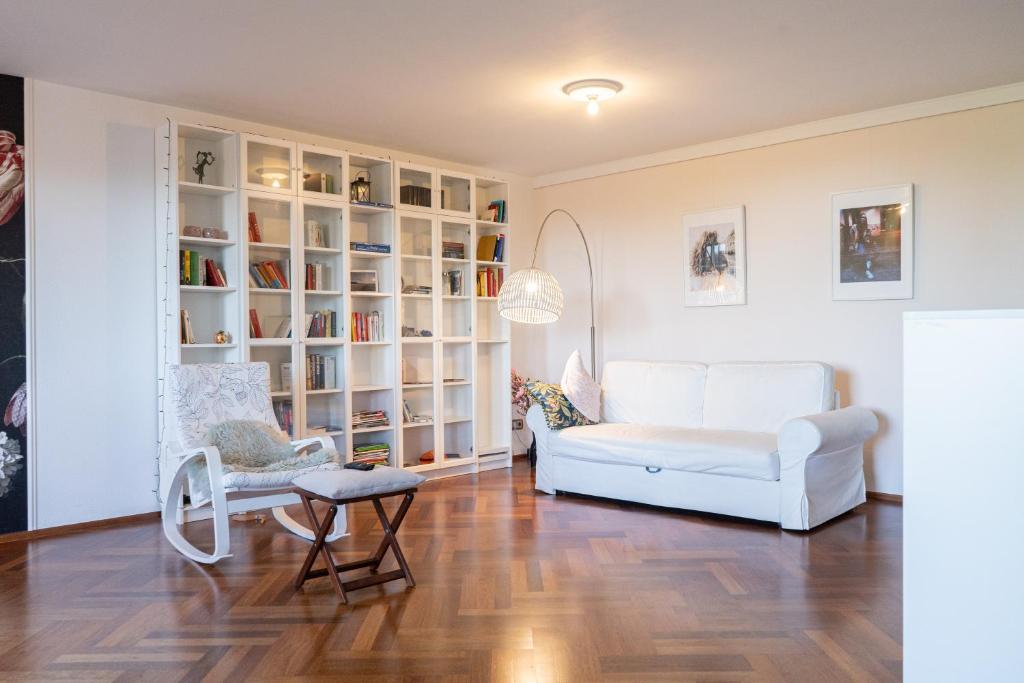 a living room with a white couch and a chair at Elegante Ferienwohnung am See in Düsseldorf
