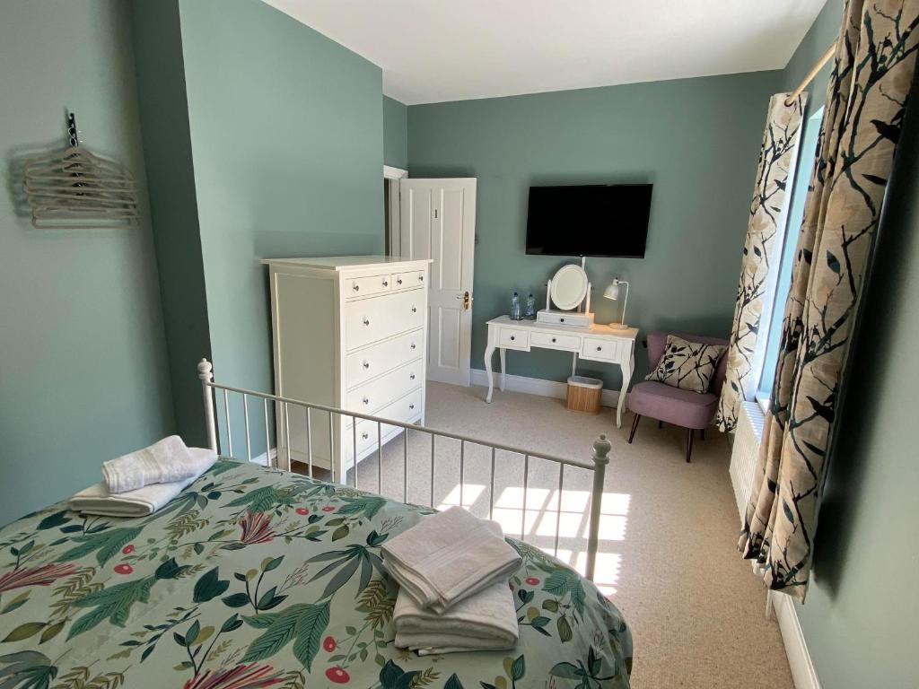 a bedroom with a bed and a dresser and a television at Brooklands Guest House in Llandrindod Wells