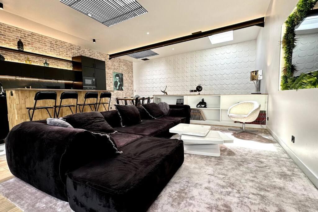una sala de estar con un gran sofá negro y sillas en Loft entre Paris et Disney, en Le Perreux-Sur-Marne