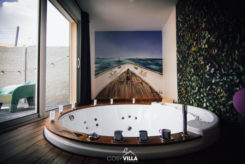 La salle de bains est pourvue d'une baignoire et d'une peinture murale. dans l'établissement CosyVilla - Spa Sauna Hammam, 