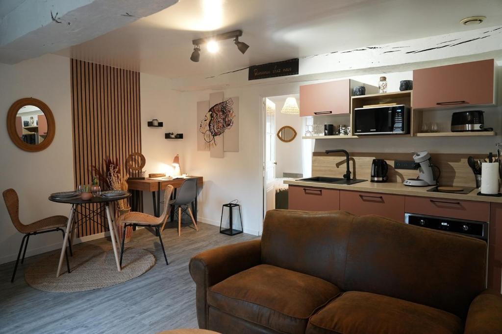 Il comprend un salon avec un canapé et une table. dans l'établissement Le Joli’Mans, appartement refait à neuf, entièrement équipé, pour 2 personnes, proche quartier historique et centre, au Mans