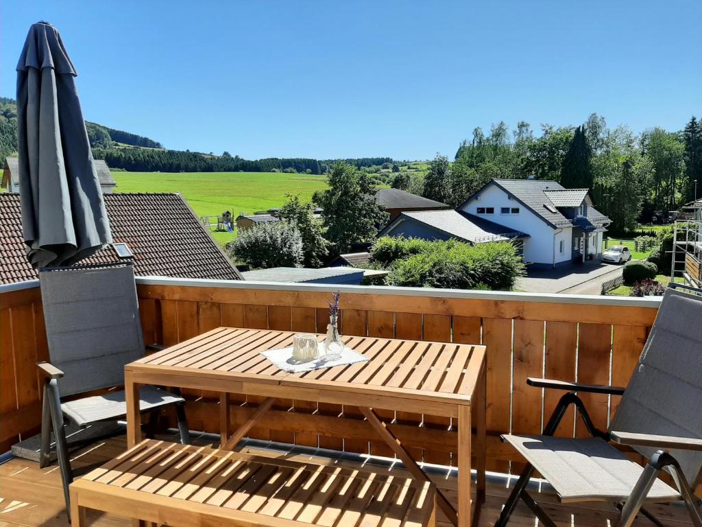 a wooden deck with a table and chairs and an umbrella at Ferienwohnung Marion in Wallenborn