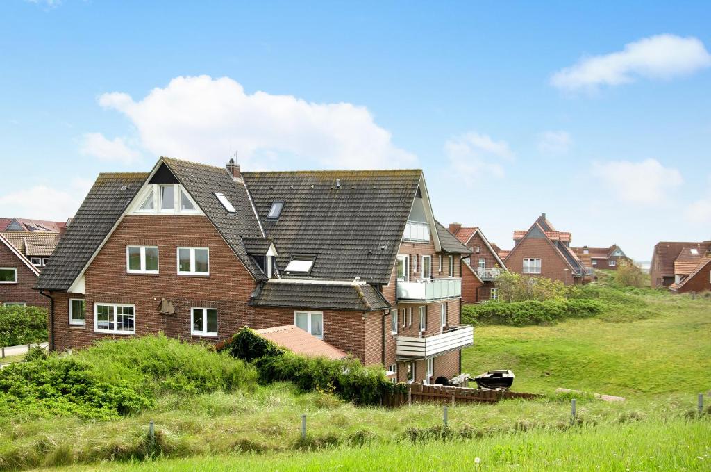 a group of houses on a hill with grass at Strandhus Uiterst-hörn Utkiek in Baltrum