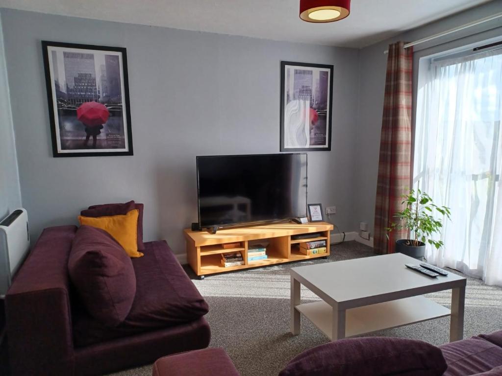 a living room with a couch and a flat screen tv at The Maltings-Old Door - Huku Kwetu Dunstable - 2 Bedroom Apartment-Spacious Business Travelers- 2nd floor Serviced Apartment -Private Parking- Free Wifi in Dunstable