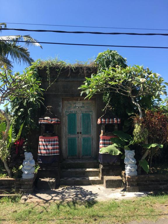 a small house with a green door and two chairs at Kubu Pering in Keramas