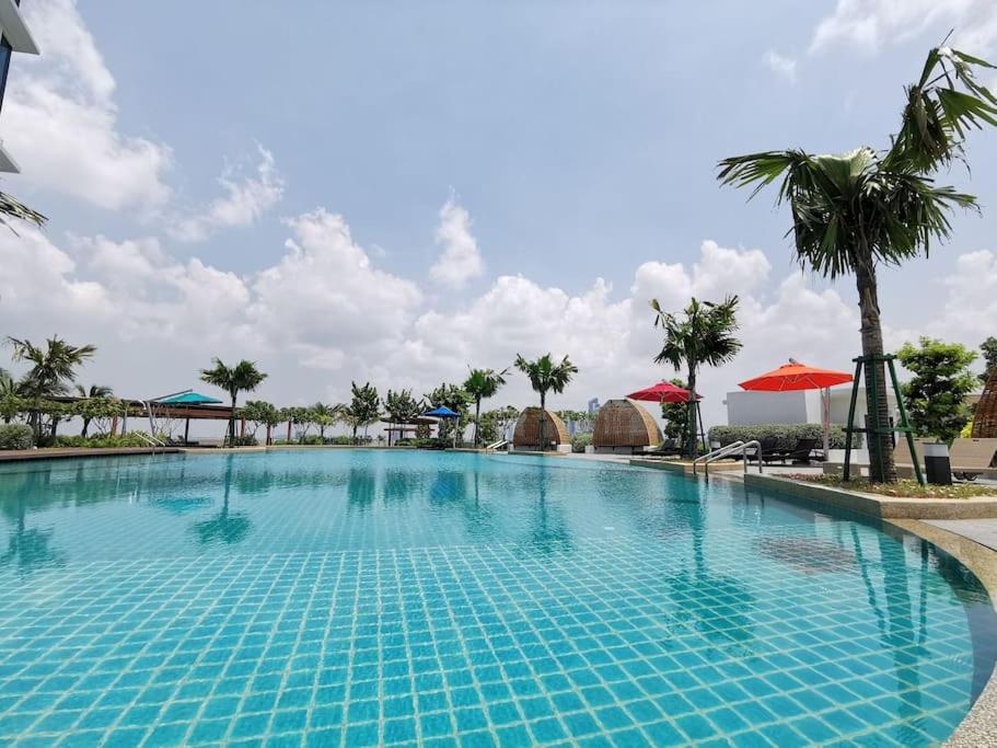 una piscina en el complejo con palmeras y sombrillas en C1108 Almas Suites Muji Studio100mbpsNetflix STAY, en Nusajaya