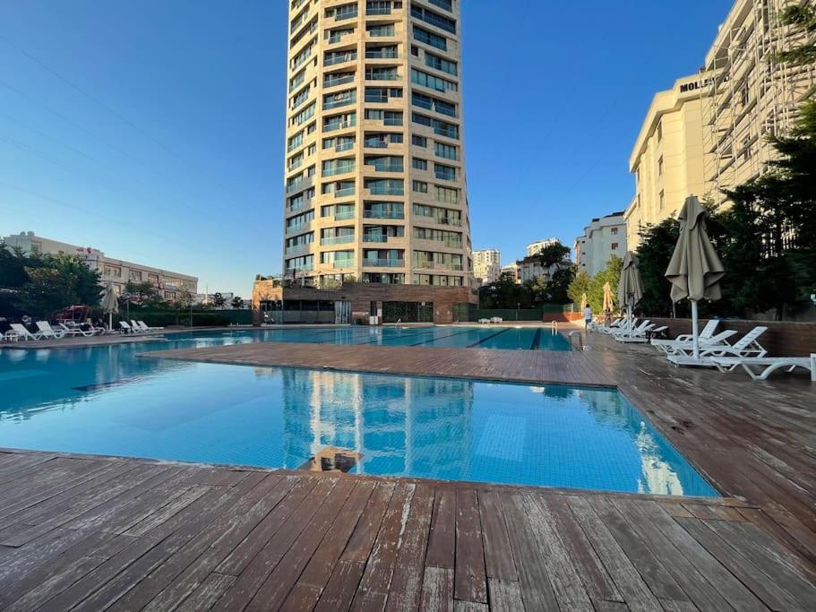 a large swimming pool with chairs and a tall building at Newada Residence 1+1 With Pool View in Istanbul