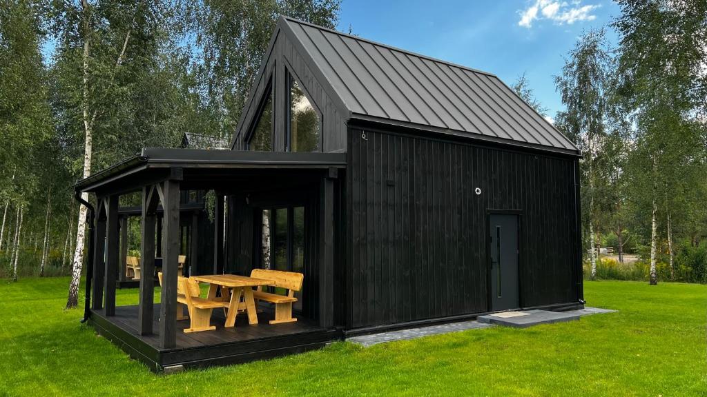 a black shed with a table in the grass at Domki u Ralfiego in Łuka