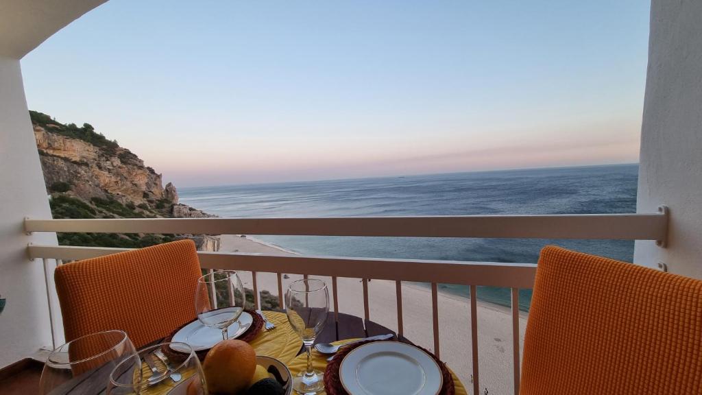 a table on a balcony with a view of the ocean at Sesimbra Sun&Sea - Beachfront Apartment! in Sesimbra
