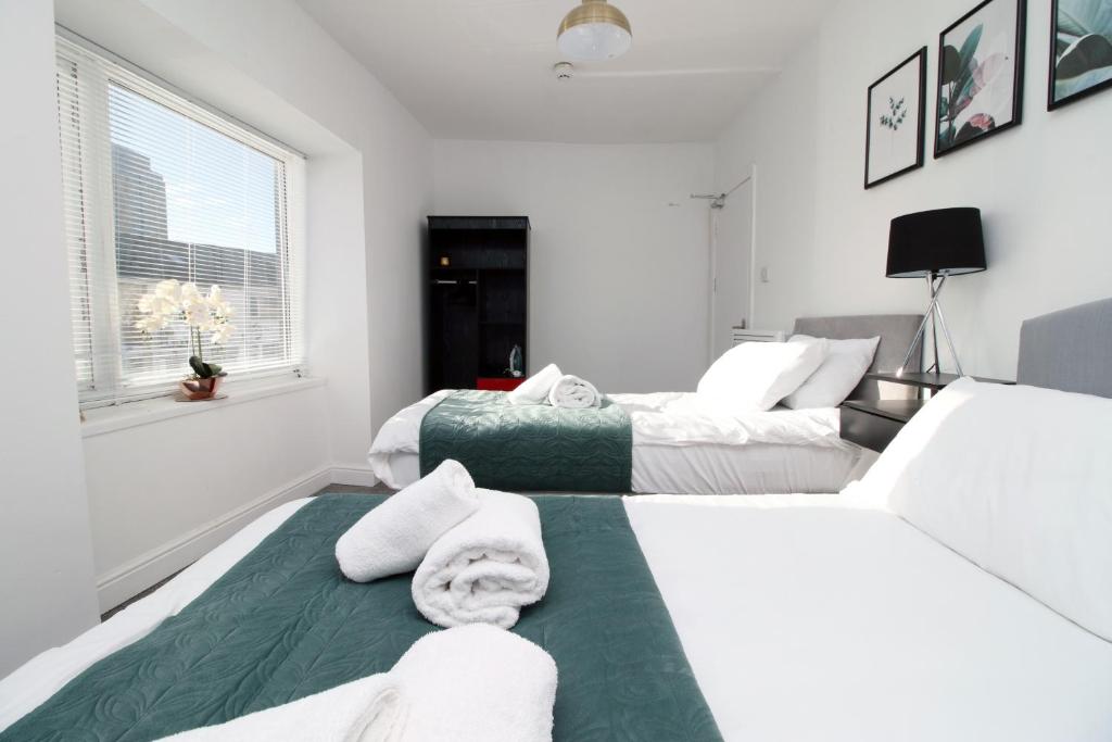 Duas camas num quarto com paredes brancas em Spacious 5 Bedroom Apartment In Swansea em Swansea
