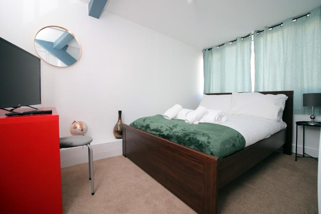 ein Schlafzimmer mit einem Bett, einem Spiegel und einem Fernseher in der Unterkunft Spacious 5 Bedroom Apartment In Swansea in Swansea