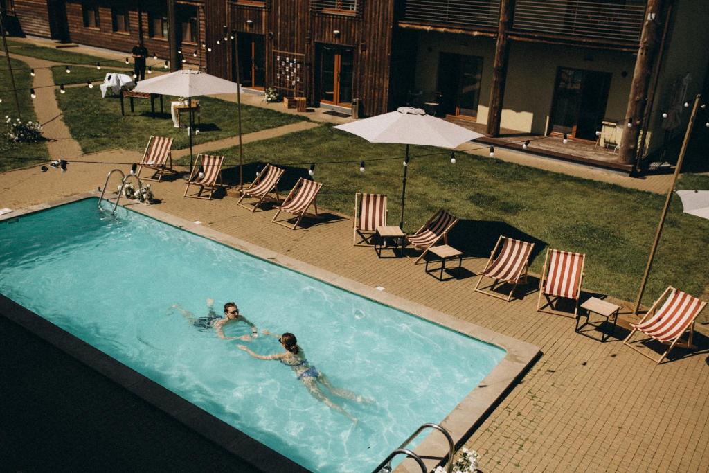 2 persone che nuotano in una piscina con sedie e ombrelloni di Eden Resort a Yasnogorodka