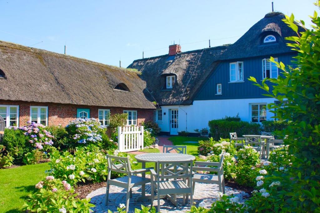 a table and chairs in the yard of a house at Landhaus am Meer - Whg 5 Hilligenlei in Utersum