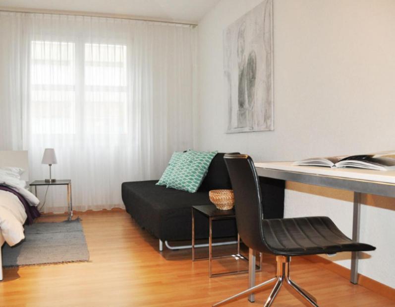 uma sala de estar com uma secretária e um sofá em Nest - Poststrasse 24 em Zug
