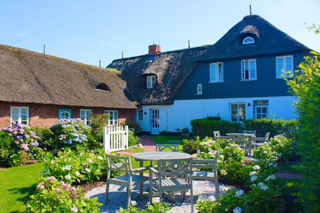 a house with a table and chairs in the yard at Landhaus am Meer - Whg 8 Westerley in Utersum