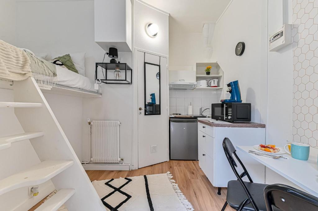 une petite cuisine blanche avec un bureau et une table dans l'établissement Studio cosy proche Paris - 2 min RER Gentilly, à Gentilly