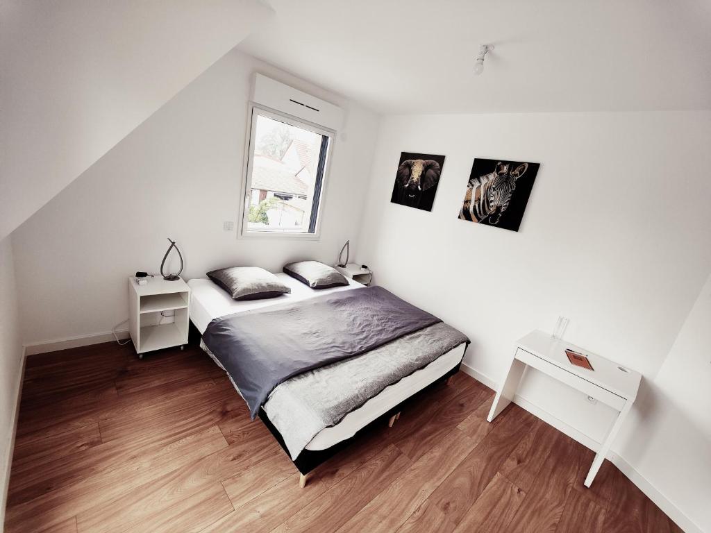 a white bedroom with a bed and a window at Appartement 48m², Strasbourg centre à 15 min en train in Fegersheim