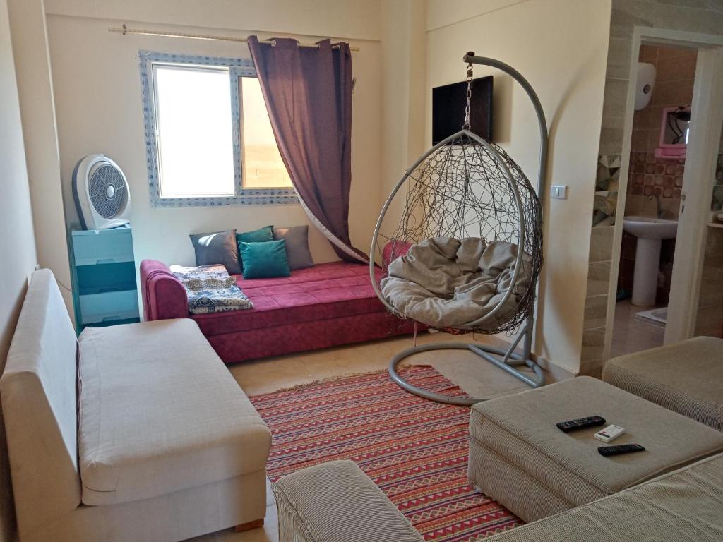 uma sala de estar com um baloiço e um sofá em استوديو عائلات فقط الساحل الشمالي ريتال فيو em Al Ḩammām