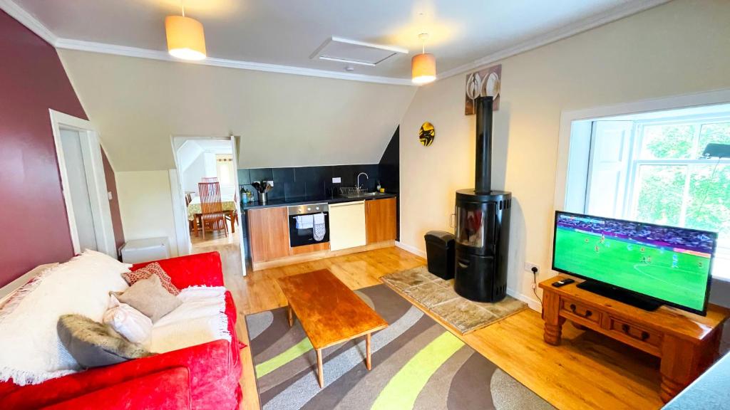 a living room with a red couch and a flat screen tv at Catcune Family Suite in Gorebridge