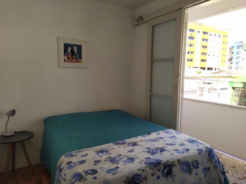 a bedroom with a bed and a window at Apartamento 3 minutos da orla in Capão da Canoa