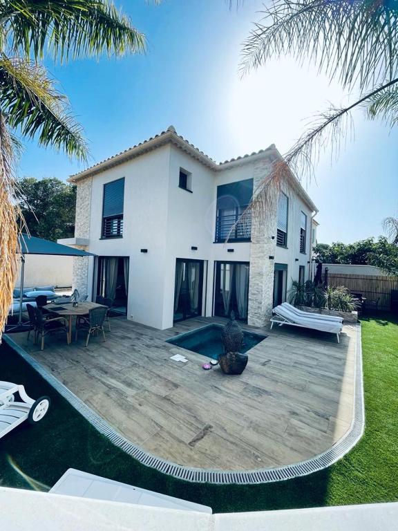 une grande maison blanche avec une terrasse en bois devant dans l'établissement Villa Natural Zen Rayolet, à Six-Fours-les-Plages