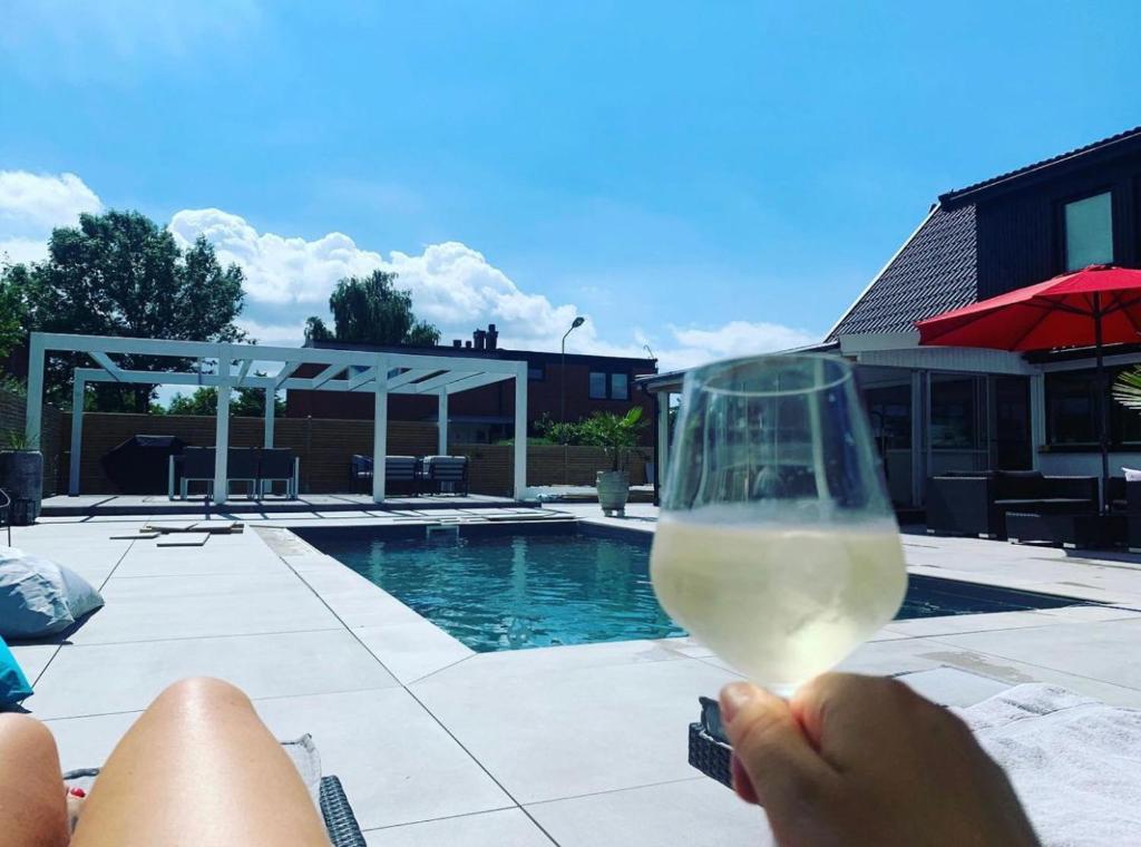 a person holding a glass of wine near a swimming pool at Luxurious house 20 minutes from Malmö Arena 