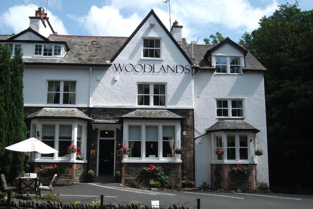 a white inn with a sign on the front of it at Woodlands in Windermere