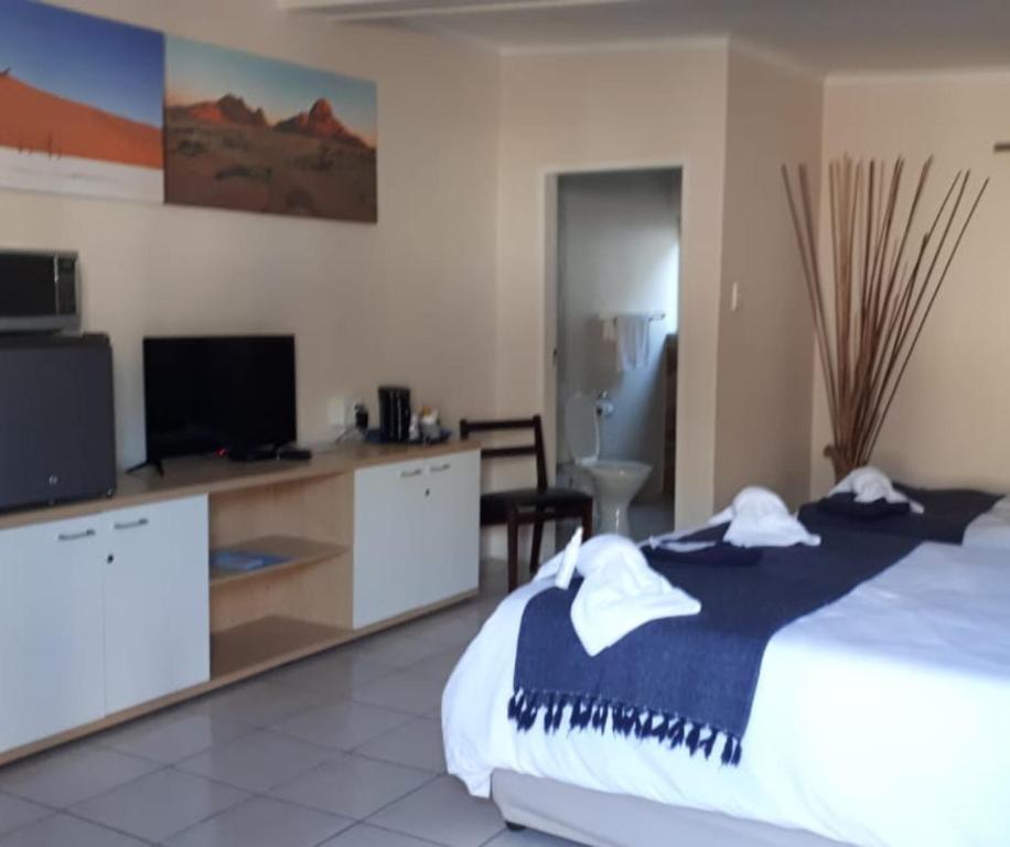 a bedroom with a bed and a desk with a tv at The Mole Guesthouse in Swakopmund