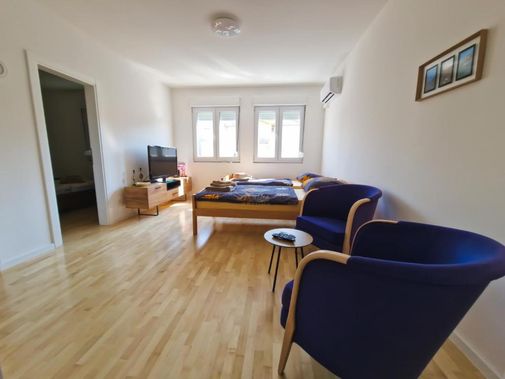 - une chambre avec un lit et deux chaises bleues dans l'établissement Apartment Ventura, à Mostar