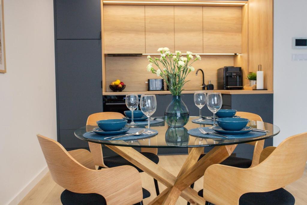 a dining room table with chairs and a vase of flowers at Apartament Aleksandra SPA Dziwnów in Dziwnów