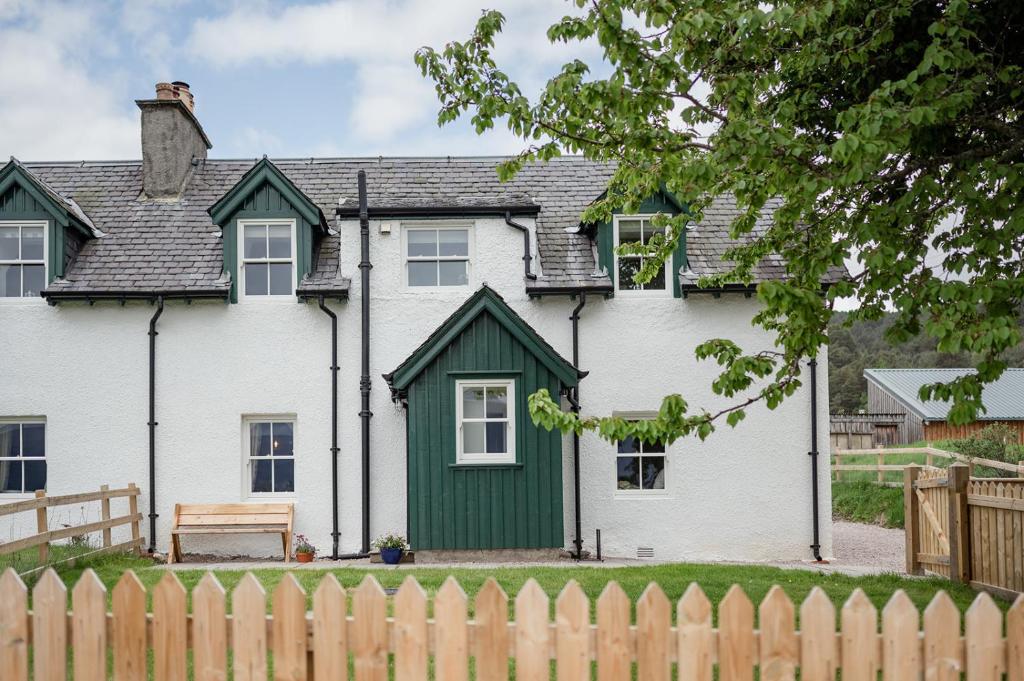een wit huis met een groene deur en een hek bij Beinn Cottage - Seasgair Lodges in Kincraig