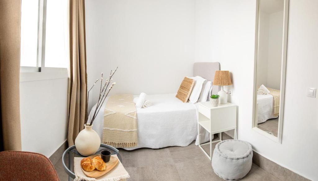 um quarto branco com uma cama e um espelho em Apartamentos Casa Macías em Cádiz