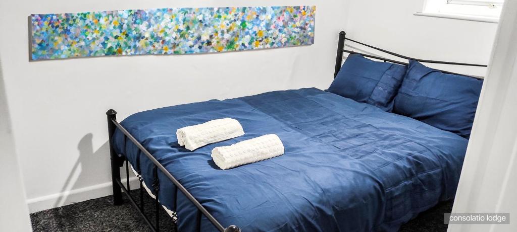 Una cama azul con dos almohadas blancas. en Consolatio Lodge, en Great Yarmouth