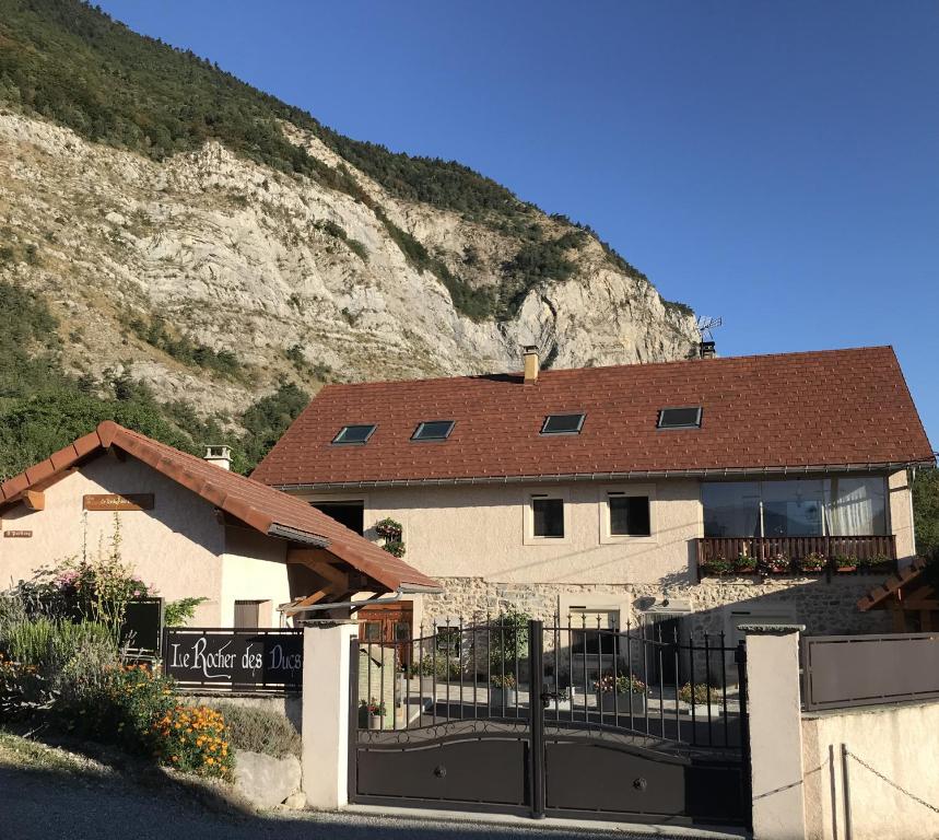 una casa con una valla delante de una montaña en Le Rocher des Ducs, vue sur montagne avec abris motos, en Le Glaizil